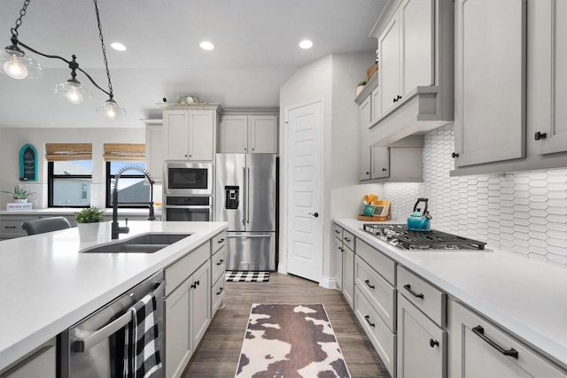 kitchen with appliances with stainless steel finishes, dark hardwood / wood-style flooring, beverage cooler, sink, and decorative light fixtures