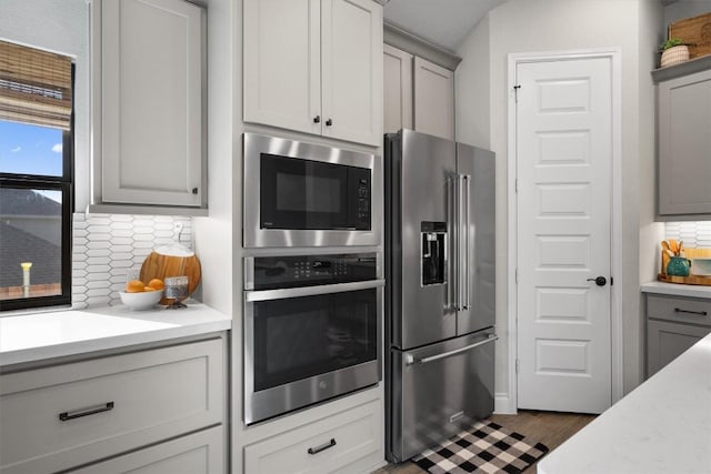 kitchen featuring gray cabinetry, decorative backsplash, stainless steel fridge, and built in microwave