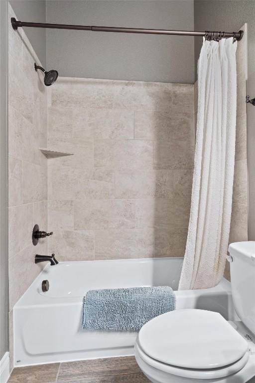 bathroom featuring shower / bath combination with curtain, toilet, and wood-type flooring