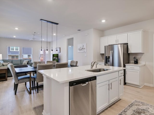 193 Standing Rock Ln, Marble Falls, TX 78654 - kitchen with appliances with stainless steel finishes, a sink, open floor plan, a center island with sink, and light wood finished floors