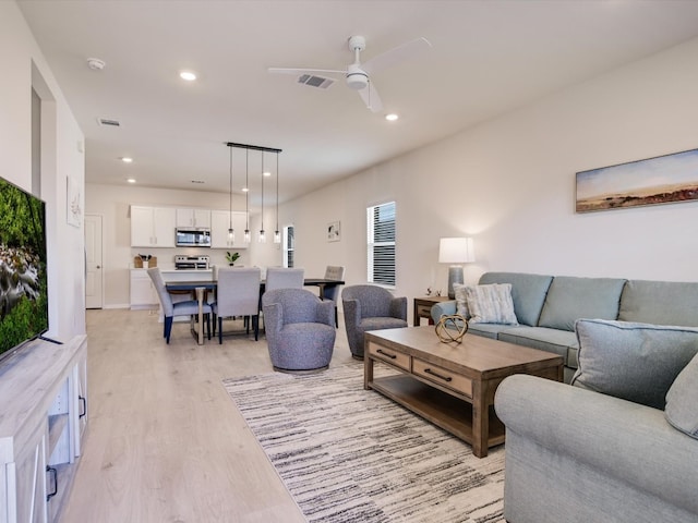 living room with light hardwood / wood-style flooring and ceiling fan