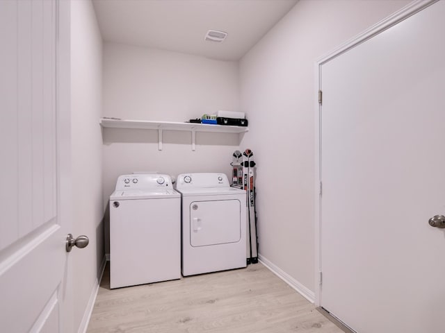 clothes washing area with light hardwood / wood-style flooring and washing machine and dryer