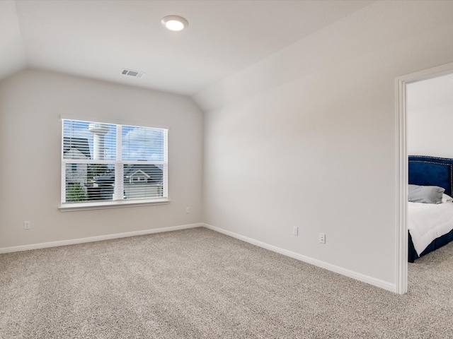 empty room featuring carpet flooring and lofted ceiling