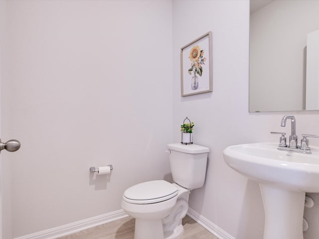 bathroom with toilet, sink, and hardwood / wood-style floors