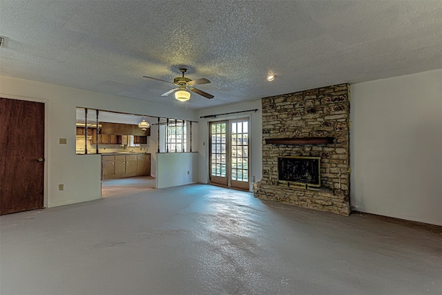 unfurnished living room featuring ceiling fan, a textured ceiling, a stone fireplace, and french doors