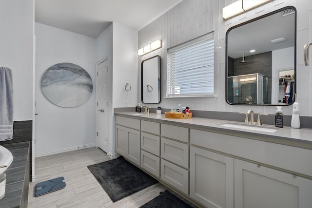8712 Mina Dr, Austin, TX 78747 - bathroom featuring a stall shower, double vanity, baseboards, and wood finished floors
