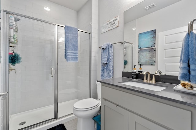 bathroom featuring toilet, vanity, and a shower with door