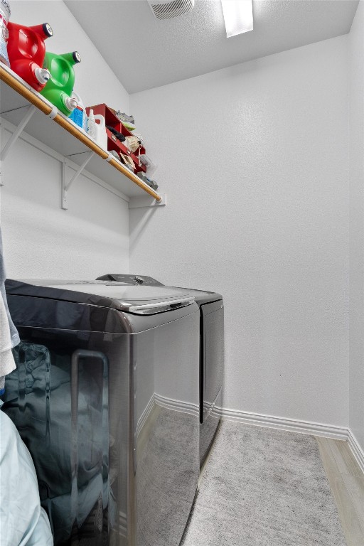 washroom with washing machine and clothes dryer and wood-type flooring