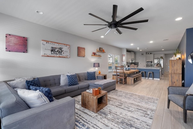 living room featuring ceiling fan, sink, and light hardwood / wood-style flooring