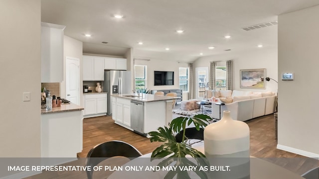 kitchen featuring white cabinetry, appliances with stainless steel finishes, backsplash, a kitchen island with sink, and dark hardwood / wood-style flooring