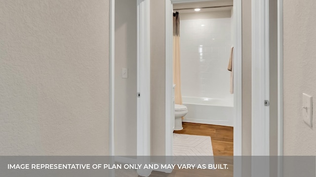 bathroom with hardwood / wood-style floors, bathing tub / shower combination, and toilet