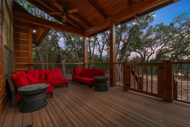 deck at dusk with ceiling fan and an outdoor living space with a fire pit