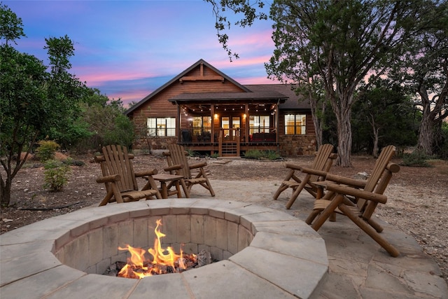 patio terrace at dusk featuring an outdoor fire pit and a deck