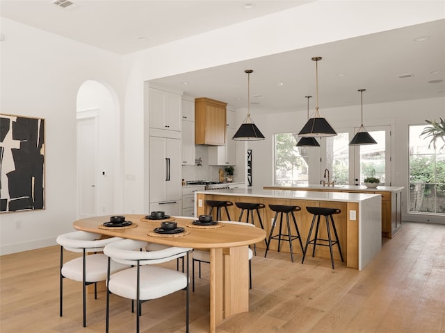 interior space featuring hanging light fixtures, white cabinets, a spacious island, and paneled refrigerator