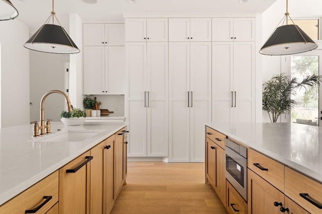 kitchen featuring white cabinets, pendant lighting, and sink