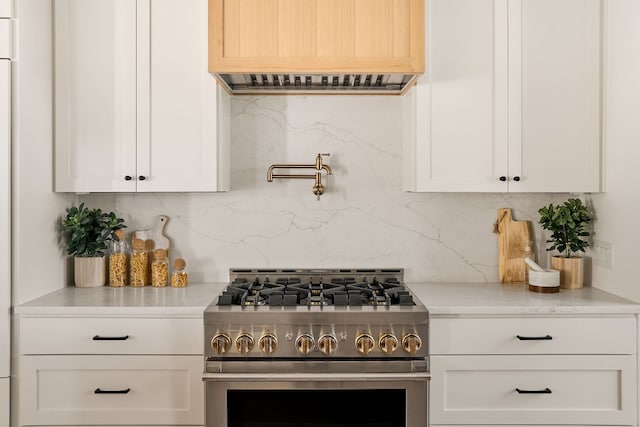 kitchen featuring white cabinets, decorative backsplash, and high end range