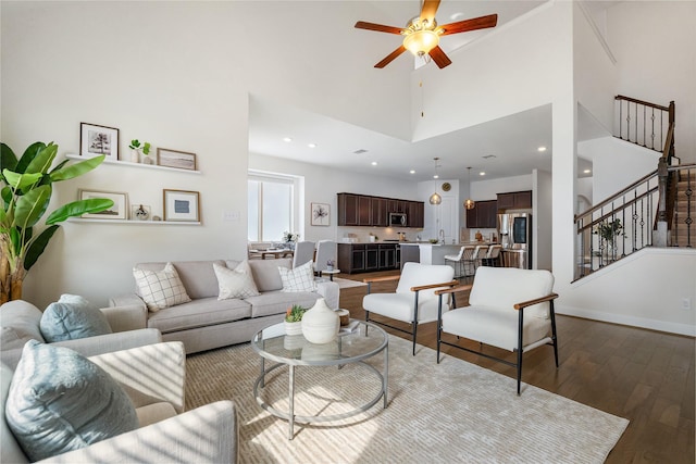 living room featuring a towering ceiling, hardwood / wood-style floors, and ceiling fan