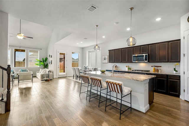 kitchen featuring stainless steel appliances, sink, a kitchen bar, tasteful backsplash, and an island with sink