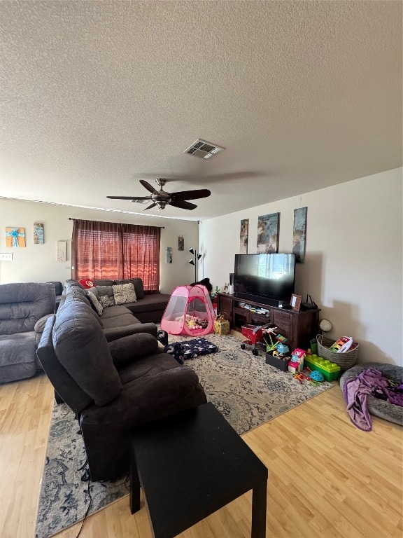 living room featuring hardwood / wood-style floors, a textured ceiling, and ceiling fan