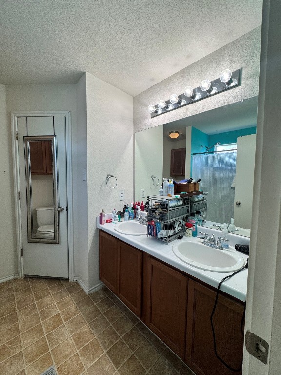 bathroom featuring toilet, vanity, and a textured ceiling