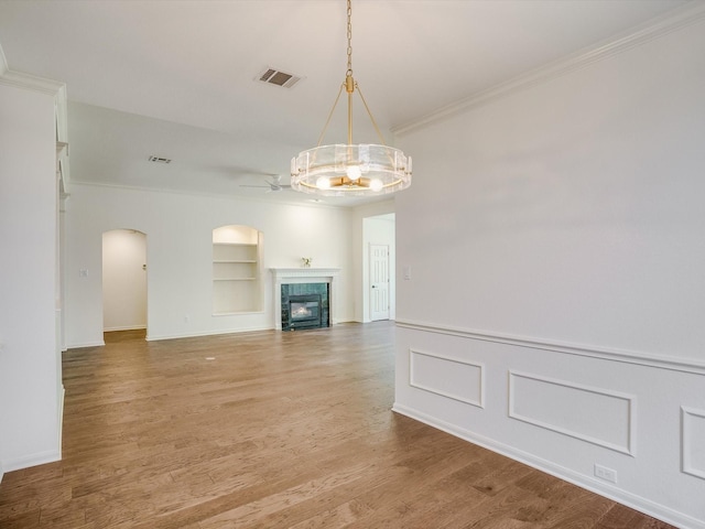 unfurnished living room with ceiling fan, crown molding, hardwood / wood-style flooring, and built in shelves