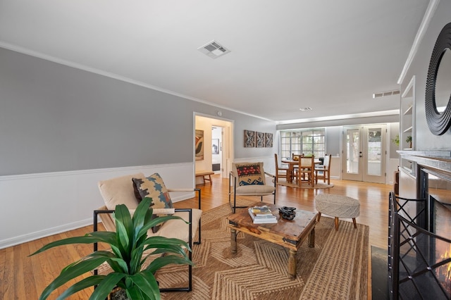 living room featuring ornamental molding, french doors, and light hardwood / wood-style flooring