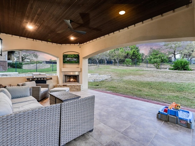 patio terrace at dusk featuring an outdoor living space with a fireplace and ceiling fan