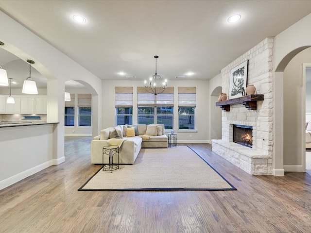 living room with light wood-type flooring, a fireplace, and an inviting chandelier