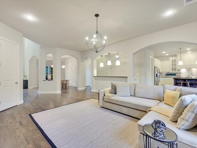 living room with dark wood-type flooring, sink, and an inviting chandelier