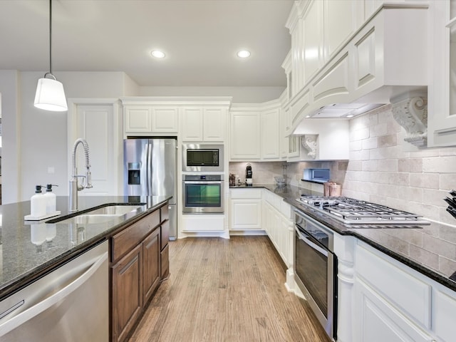 kitchen featuring stainless steel appliances, light hardwood / wood-style floors, white cabinetry, dark stone countertops, and decorative backsplash