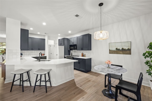 kitchen featuring kitchen peninsula, light hardwood / wood-style flooring, hanging light fixtures, and sink