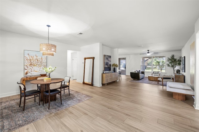 dining area featuring ceiling fan with notable chandelier and light hardwood / wood-style flooring