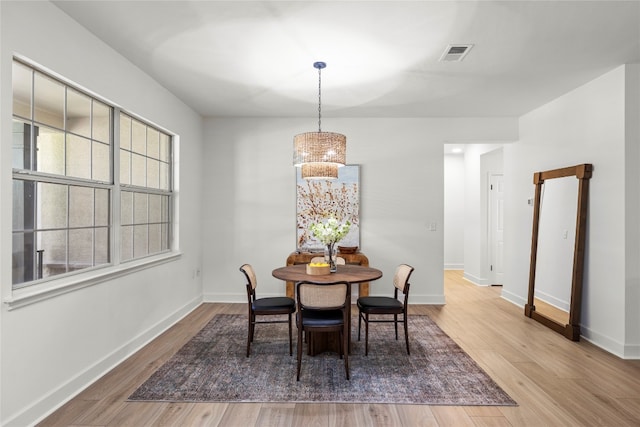 dining space with hardwood / wood-style floors and an inviting chandelier