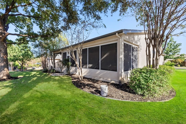 view of side of home featuring a sunroom and a yard