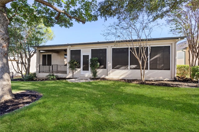 back of property with a sunroom and a lawn