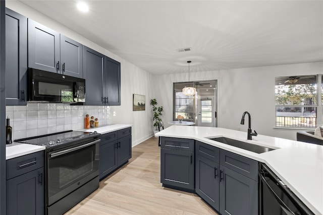 kitchen featuring light hardwood / wood-style floors, sink, black appliances, tasteful backsplash, and pendant lighting