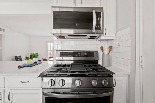 kitchen featuring stainless steel appliances, visible vents, white cabinets, and backsplash