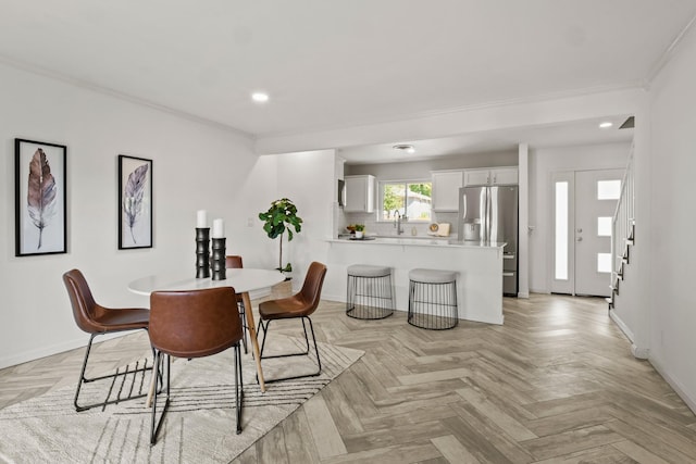 dining space featuring crown molding, sink, and light parquet flooring