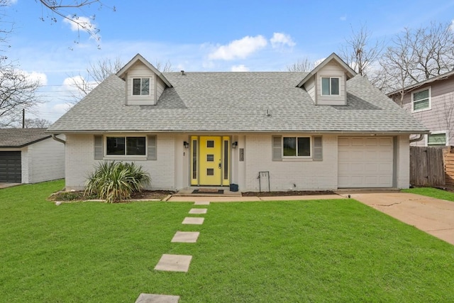 view of front of house featuring roof with shingles, brick siding, a front yard, a garage, and driveway