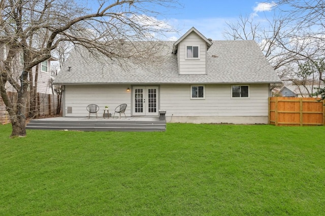 back of property featuring french doors, a lawn, and fence