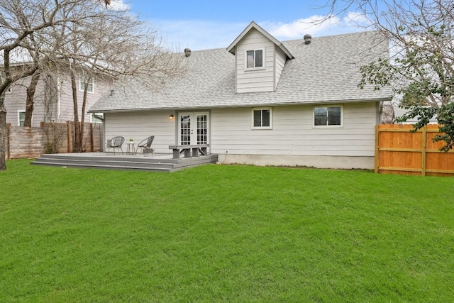 rear view of property with a fenced backyard, roof with shingles, a lawn, and french doors