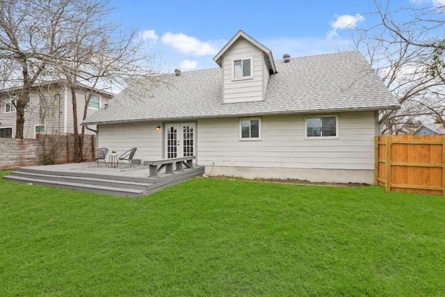 rear view of house with a shingled roof, french doors, a lawn, and a deck