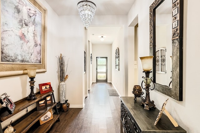 corridor with dark wood-type flooring and a notable chandelier