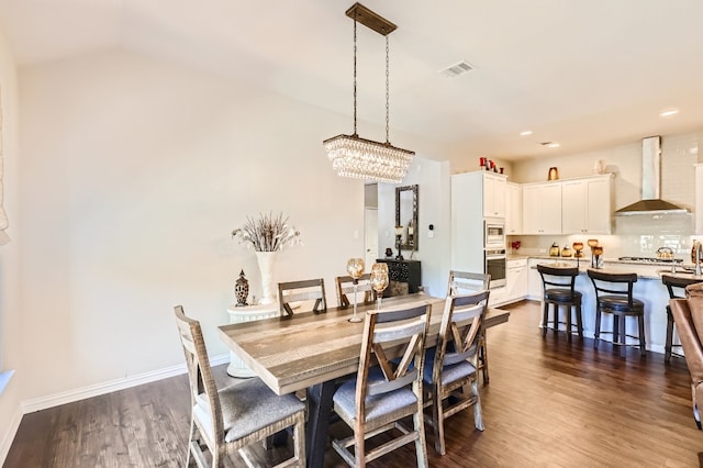 dining space featuring dark hardwood / wood-style floors, lofted ceiling, and a notable chandelier