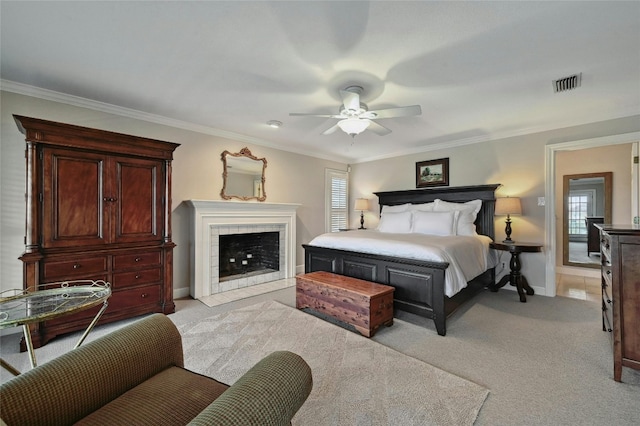 carpeted bedroom featuring ceiling fan, ornamental molding, and a tiled fireplace