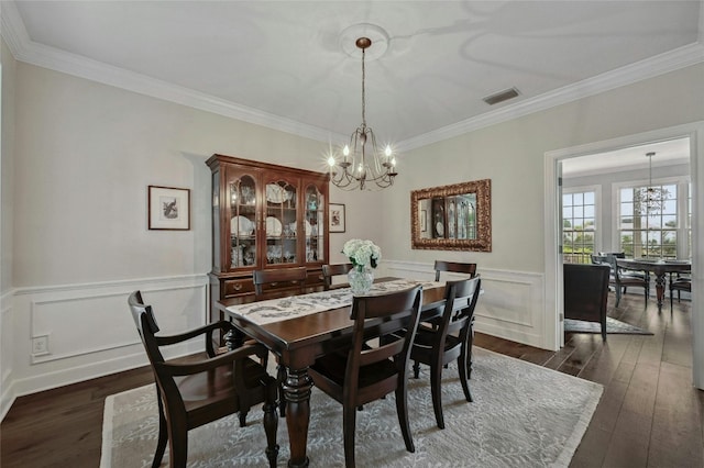 dining space with crown molding, dark wood-type flooring, and a notable chandelier