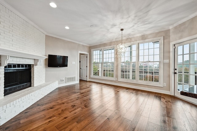 unfurnished living room with hardwood / wood-style flooring, a brick fireplace, and plenty of natural light