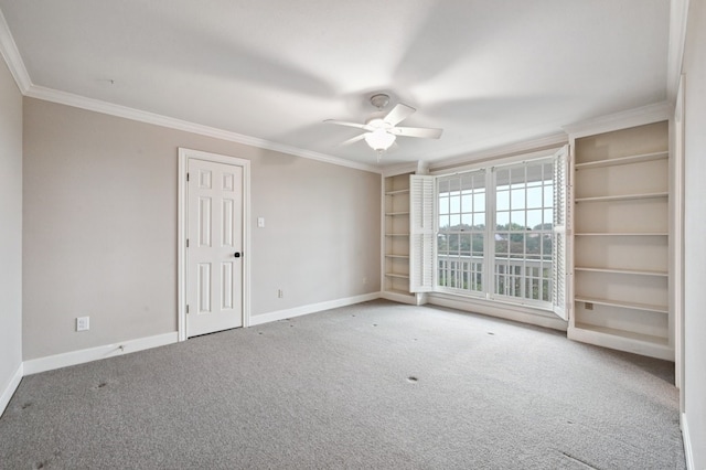 carpeted spare room featuring ceiling fan, ornamental molding, and built in shelves