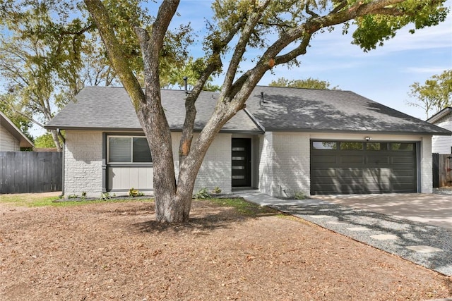mid-century home featuring fence, a garage, driveway, and brick siding