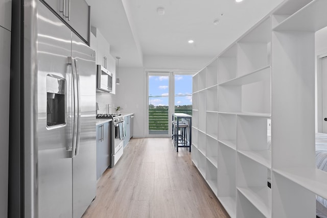 kitchen with light hardwood / wood-style floors, white cabinetry, and appliances with stainless steel finishes